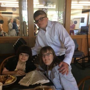 Picture of three adults with CHARGE: Kristin and Ashley are seated, with Win standing behind them