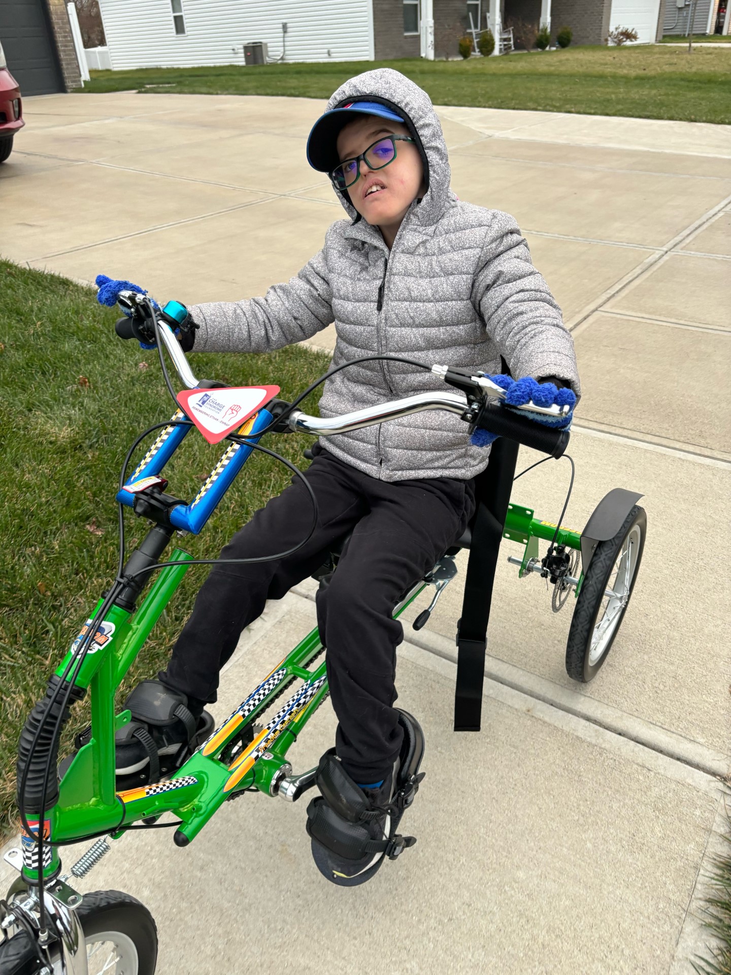 A boy rides a green adaptive coat wearing a coat. 