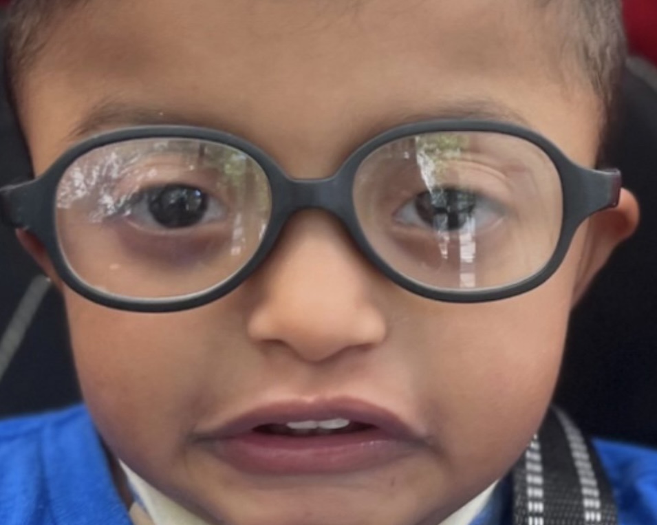 Close up photo of a young boy with glasses.