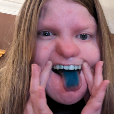 girl with long blonde hair sticks out blue tongue
