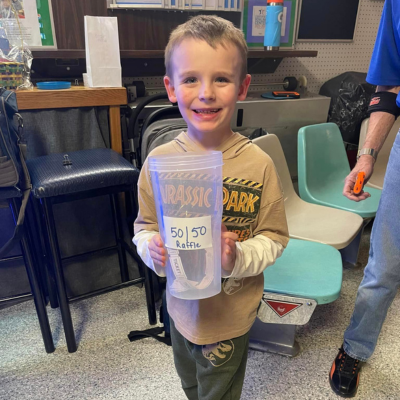 Young boy holds a 50/50 raffle cup. 