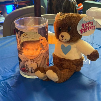 Candle with photo of baby Tucker sits next to a bear with a blue heart shirt.