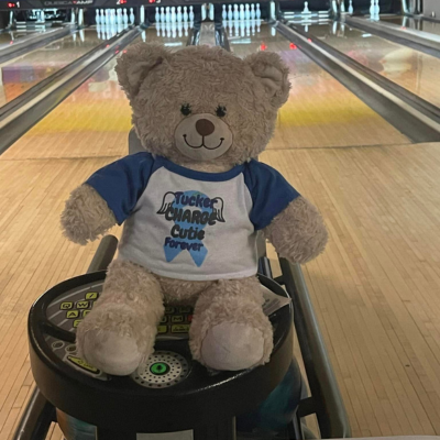 Tucker Bear sits in front of a bowling lane. 