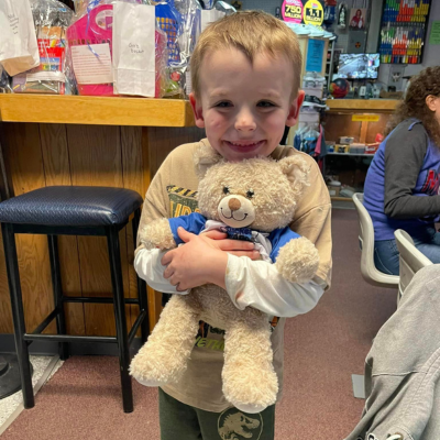 Young boy hugs a teddy bear containing his brother's ashes. 