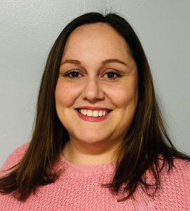 Woman in a pink top with dark brown hair smiles at the camera.