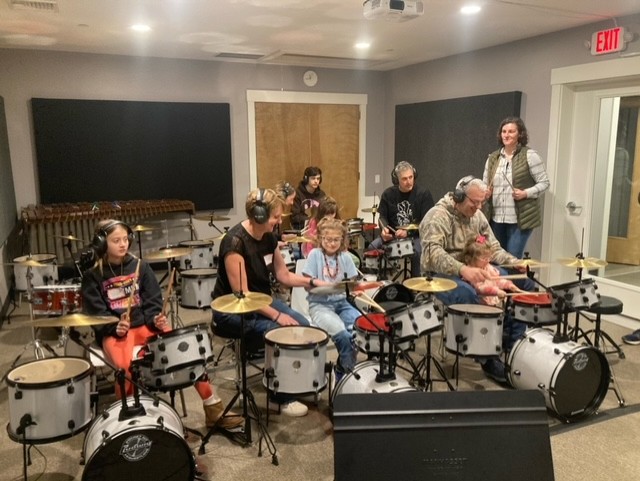 group photo of families playing drum sets