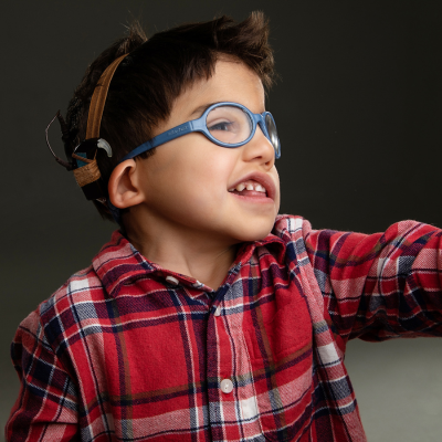 Young boy with CHARGE syndrome, wearing glasses and looking off into the distance.