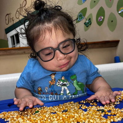 Young boy with glasses plays with corn