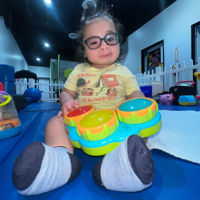 Toddler boy with glasses plays with a toy