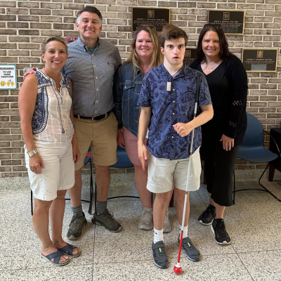 Young man with a sight cane poses with his family