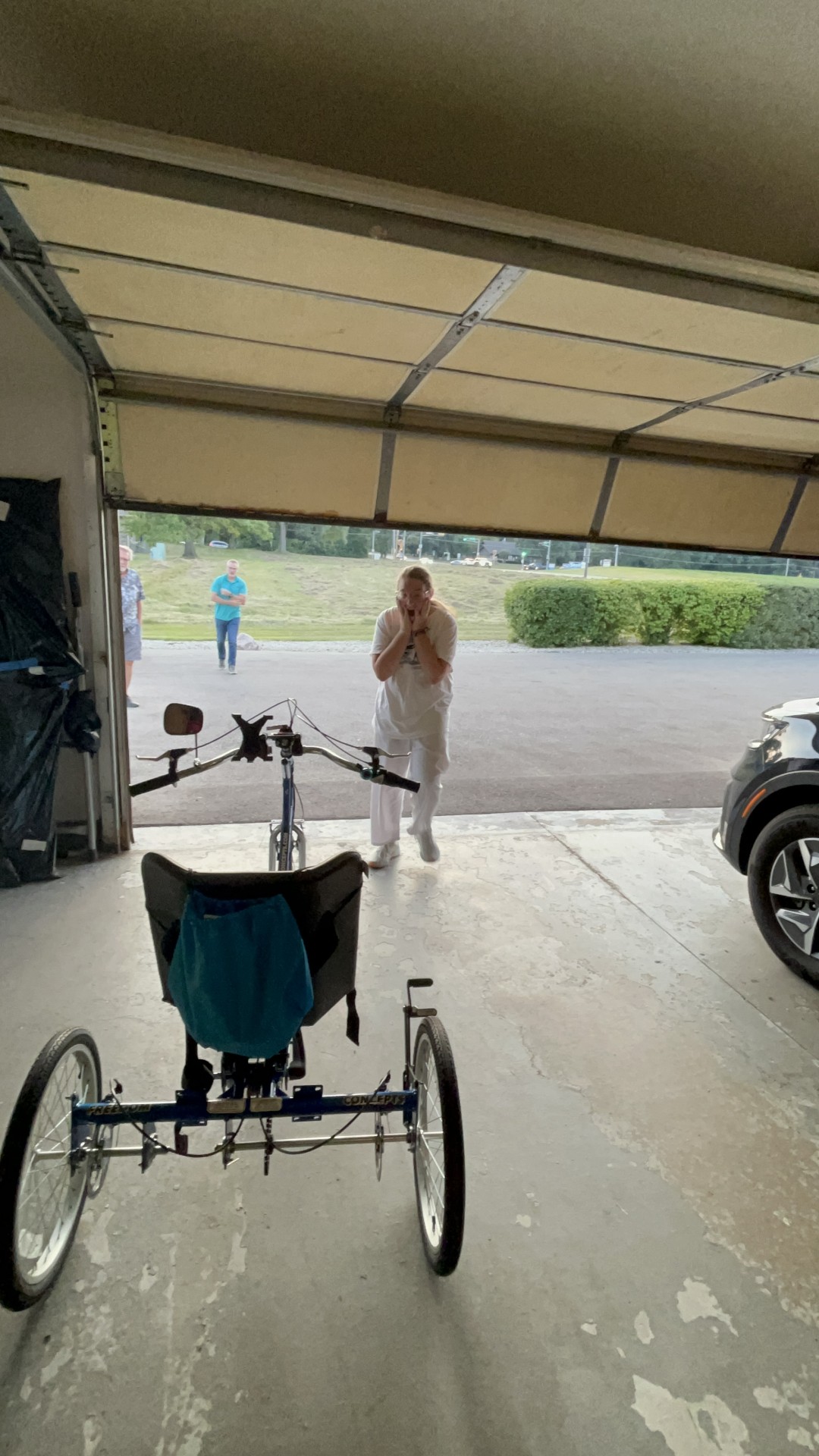 Teenage girl opening garage door, surprised to find a new adaptive bike inside. 