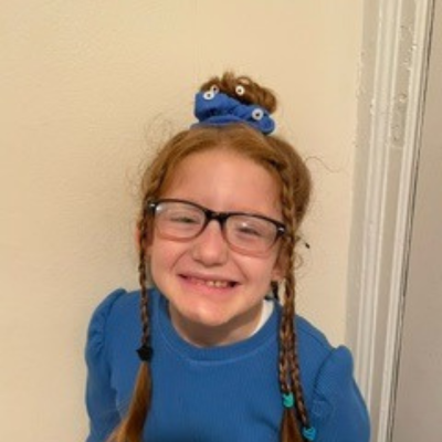  A young girl with glasses and braids smiles for the camera