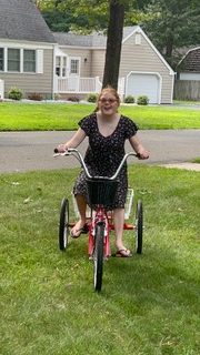 Teenage girl rides an adaptive 3-wheeled bike