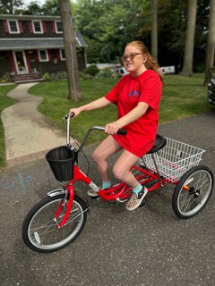 Teenage girl rides an adaptive 3-wheeled bike