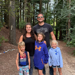 Family with two daughters and one son pose together in the forest