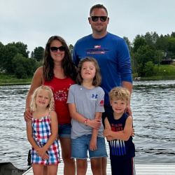 Family with two daughters and one son pose together in front of a lake