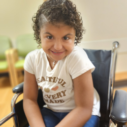 Girl with CHARGE smiling in a wheelchair
