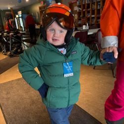 a young boy with CHARGE syndrome is dressed in ski gear ready to hit the slopes